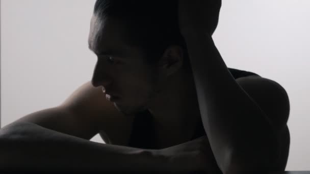 Silhouette eines depressiven, traurigen jungen Mannes, der am Tisch sitzt — Stockvideo