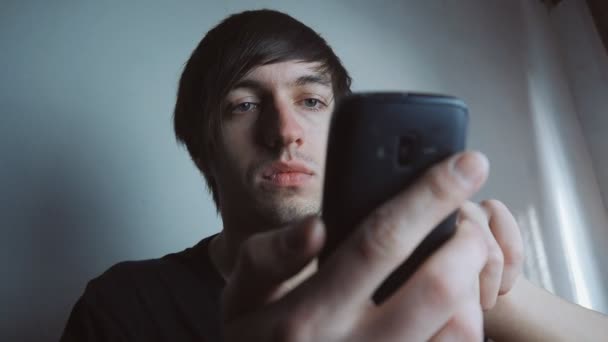 Νεαρός άνδρας χρησιμοποιώντας το smartphone στο λευκό δωμάτιο — Αρχείο Βίντεο