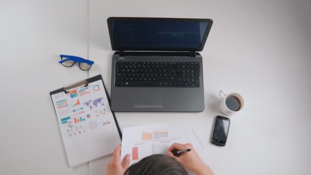 Geschäftsmann arbeitet am Schreibtisch mit Laptop, Tablet, Smartphone und anderen Arbeitsgeräten — Stockvideo