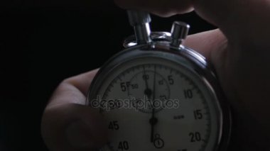 Bir kişi siyah arkaplanda kronometre çalıştırıyor