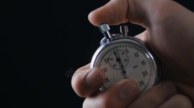 Bir kişi siyah arkaplanda kronometre çalıştırıyor