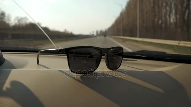 Автомобіль їде на шосе. Сонцезахисні окуляри лежать біля скла. Подорож на відпочинок — стокове відео