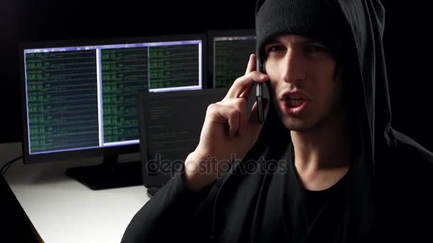 Хакер разговаривает по телефону на фоне рабочего места — стоковое видео