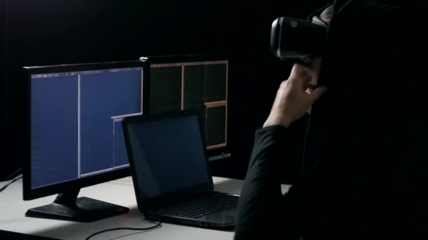 Hacker v helmě virtuální realita funguje v temné místnosti. Muž programátor získává zkušenosti s používáním Vr-sluchátka s mikrofonem. — Stock video