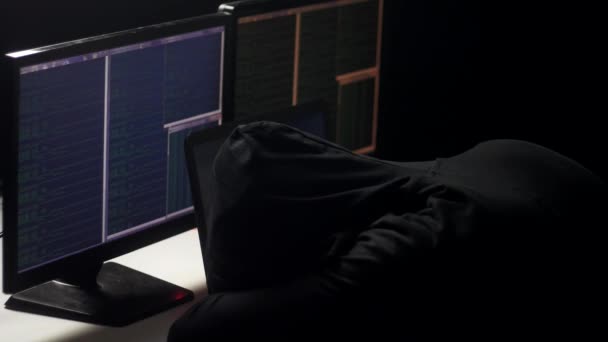 Ein müder Hacker, der in einem dunklen Raum an einem Computer arbeitet. legte er seinen Kopf auf den Tisch. Hacker arbeitet die ganze Nacht. — Stockvideo