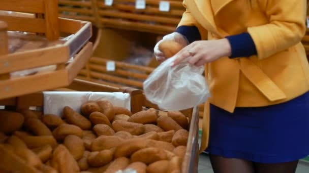 Uma mulher a pegar em pães e a metê-los no pacote. Compras no supermercado ou padaria — Vídeo de Stock