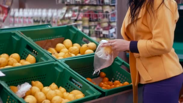 Женщина выбирает свежий лимон в продуктовом отделе . — стоковое видео