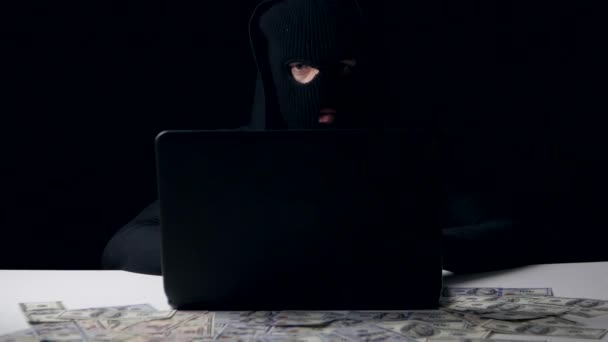 Ein Hacker mit Sturmhaube verdient Geld. Internetkriminalität. — Stockvideo