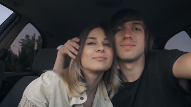 Casal jovem no amor cara e menina fazer selfie no carro. O homem está abraçando a menina — Vídeo de Stock