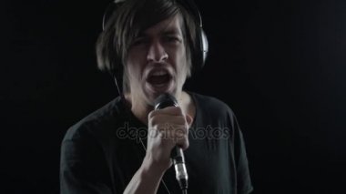 Adam rock şarkıcısı bir mikrofona söylüyor ve bir siyah arka plan üzerine başını sallar. Rock konseri kavramı