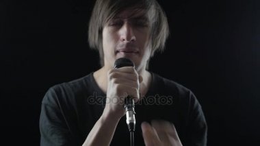 Adam rock şarkıcısı bir mikrofona söylüyor ve bir siyah arka plan üzerine başını sallar. Rock konseri kavramı