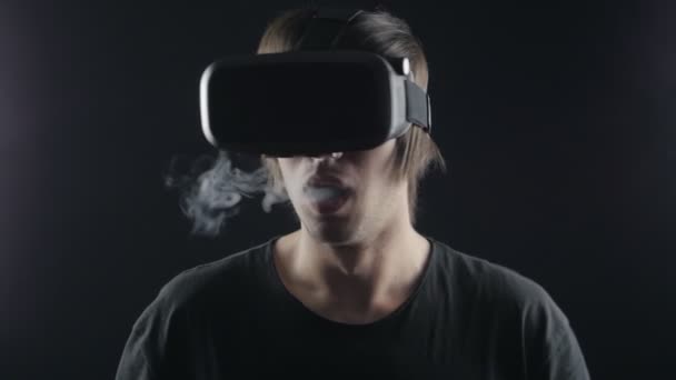Vaper man in vr hemlet exhaling clouds of smoke with e-cigarette vape in slowmotion — Stock Video