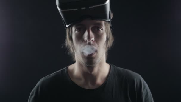 O homem fuma um cigarro eletrônico e usa um capacete de realidade virtual. Ceifeiro futurista — Vídeo de Stock