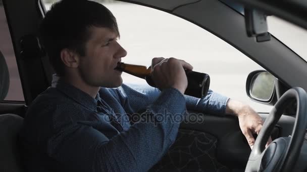 Чоловік п'є пиво в машині. П'яний водій — стокове відео