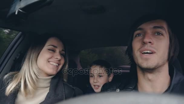 Jeune famille heureuse voyage en voiture, mari embrasse sa femme. Garçon sur le siège arrière . — Video