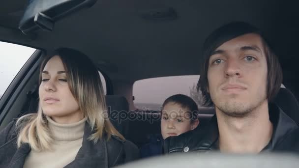 Nuori onnellinen perhe ratsastaa autolla, isä äiti ja poika — kuvapankkivideo