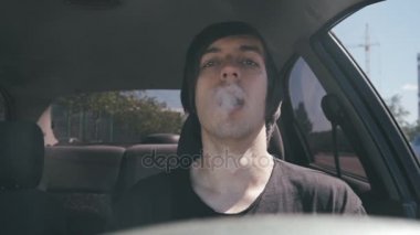 Elektronik sigara slowmotion arabada oturan adam vaper duman yapar.