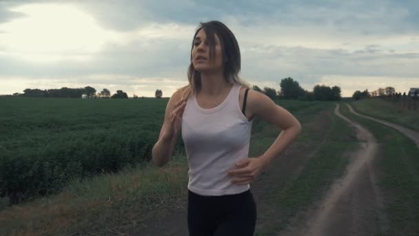 Chica atlética corriendo en la carretera en el campo. fitness al aire libre. Disparo con steadicam — Vídeo de stock