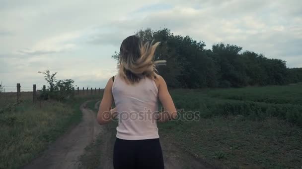 Athletic dziewczyna pracuje w road w pole. fitness na świeżym powietrzu. Strzał z steadicam — Wideo stockowe