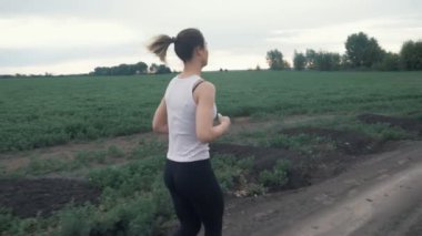 Güzel kız sabah gün doğarken alanında koşu yapıyor. açık havada fitness. Steadicam ile vurdu