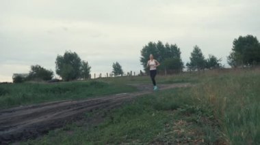 Yol alanında, koşan atletik kız. açık havada fitness. Steadicam ile vurdu