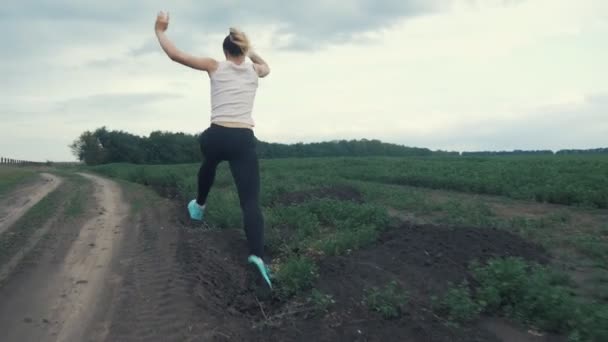 Atletische meisje draait op weg in veld. buiten fitness. Geschoten met een steadicam — Stockvideo