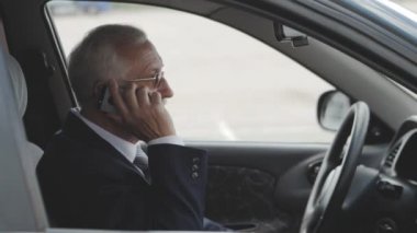 Kıdemli adam cep telefonu arabada konuşuyor