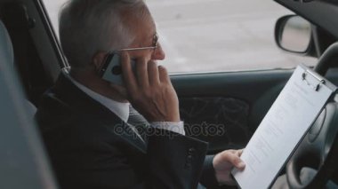 Kıdemli adam cep telefonu arabada konuşuyor