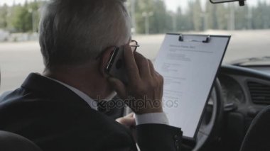 Kıdemli adam belgeleri eğitim ve arabanın içinde otururken Evet. Meşgul işadamı.