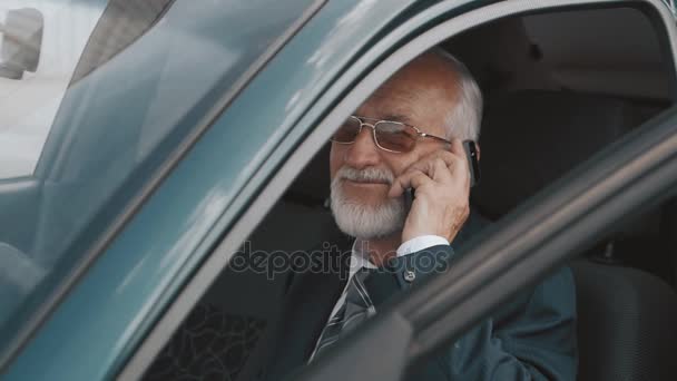 Starší muž mluví na mobilním telefonu v autě — Stock video