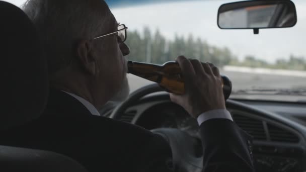 Starszy człowiek pije piwo siedząc w samochodzie. Pijany kierowca. — Wideo stockowe