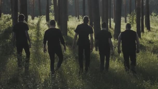 Grupo de hombres vestidos de negro van a la distancia en el bosque — Vídeo de stock