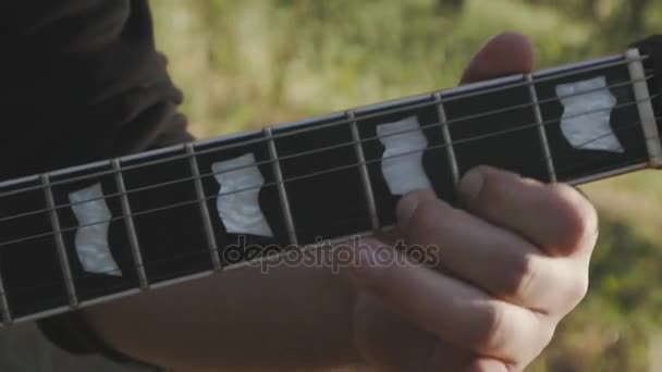 Primer plano del hombre tocando la guitarra eléctrica al aire libre en cámara lenta — Vídeos de Stock