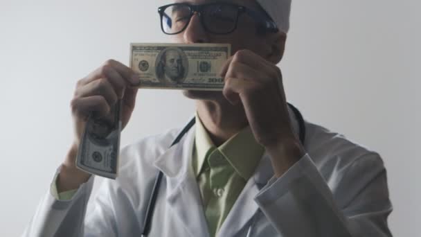 Доктор целует стодолларовую купюру. Взятка медицинскому работнику. Дорогая медицина . — стоковое видео