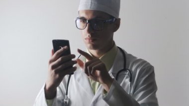 Doktor bir akıllı telefon kullanır. Tıbbi çalışan bir cep telefonu kullanarak Internet'te sörf.