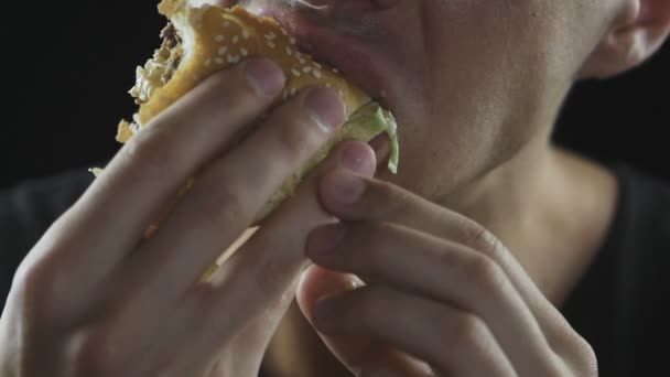 Nahaufnahme Mann isst Hamburger in Zeitlupe — Stockvideo