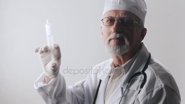 Retrato de un médico anciano con barba y gafas. El trabajador médico tiene una jeringa en sus manos. Tratamiento con inyecciones . — Vídeos de Stock