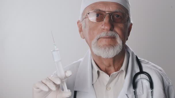 Gros plan d'un médecin âgé avec une barbe et des lunettes. Un travailleur médical tient une seringue dans ses mains. Traitement par injections . — Video