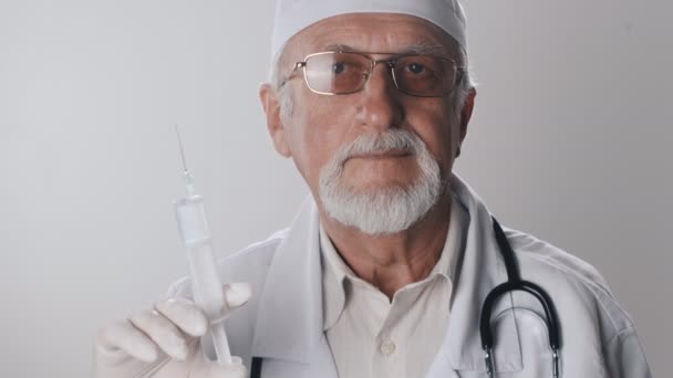 Close up of an elderly doctor with a beard and glasses. Medical worker holds a syringe in his hands. Treatment with injections. — Stock Video