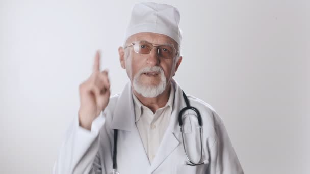Egy tapasztalt idős orvos egy szakállas és szemüveges tiltja, intett a mutatóujjával. Vigyázat, orvostudomány! — Stock videók