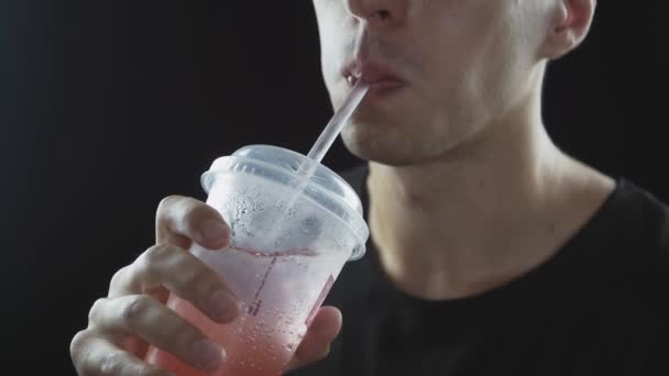 Homem bebe limonada de fast food através de uma palha, isolado em um fundo preto — Vídeo de Stock