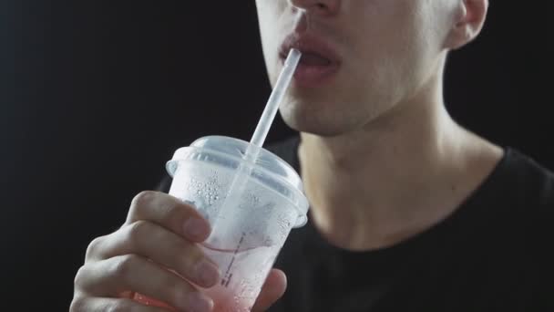 黒の背景に分離された男はファーストフード、ストローから飲み物レモネード — ストック動画
