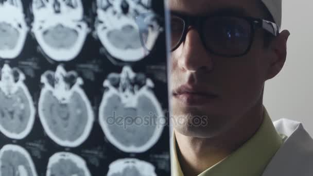 Un médico neurocirujano examina una imagen por resonancia magnética (RMN) del cerebro — Vídeo de stock