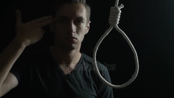 Man shows the concept of suicide. Male on the background of the loop for the neck. — Stock Video