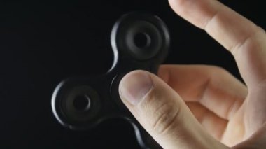 El altında siyah arka plan üzerinde dönen değer değişimi veya Kıpırdanmayı el oyuncak yakından mans
