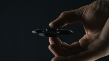 El altında siyah arka plan üzerinde dönen değer değişimi veya Kıpırdanmayı el oyuncak yakından mans