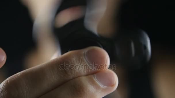 Hombre jugando con fidget spinner en fondo negro — Vídeos de Stock