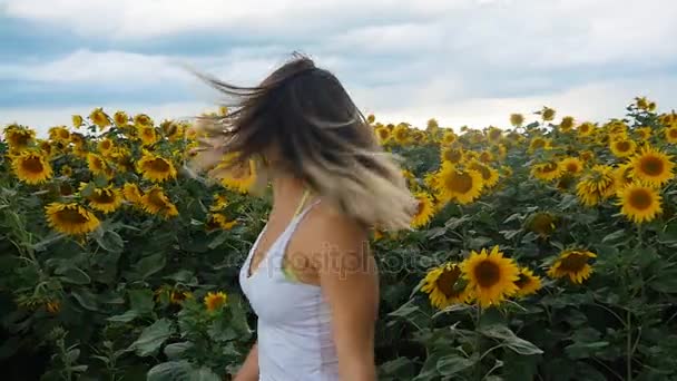 Ritratto di giovane donna in canottiera bianca in un campo di girasoli. Nuvole di tempesta sullo sfondo . — Video Stock