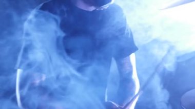 Davulcu Sahne Alanı'nda ayarla davul çalıyor. Performans rock, punk, heavy metal grubu.