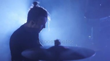 Genç bir erkek davulcu davulunun üstündeki oynamaya yakın çekim ayarlayın. Müzik video punk, ağır metal veya rock grubu.